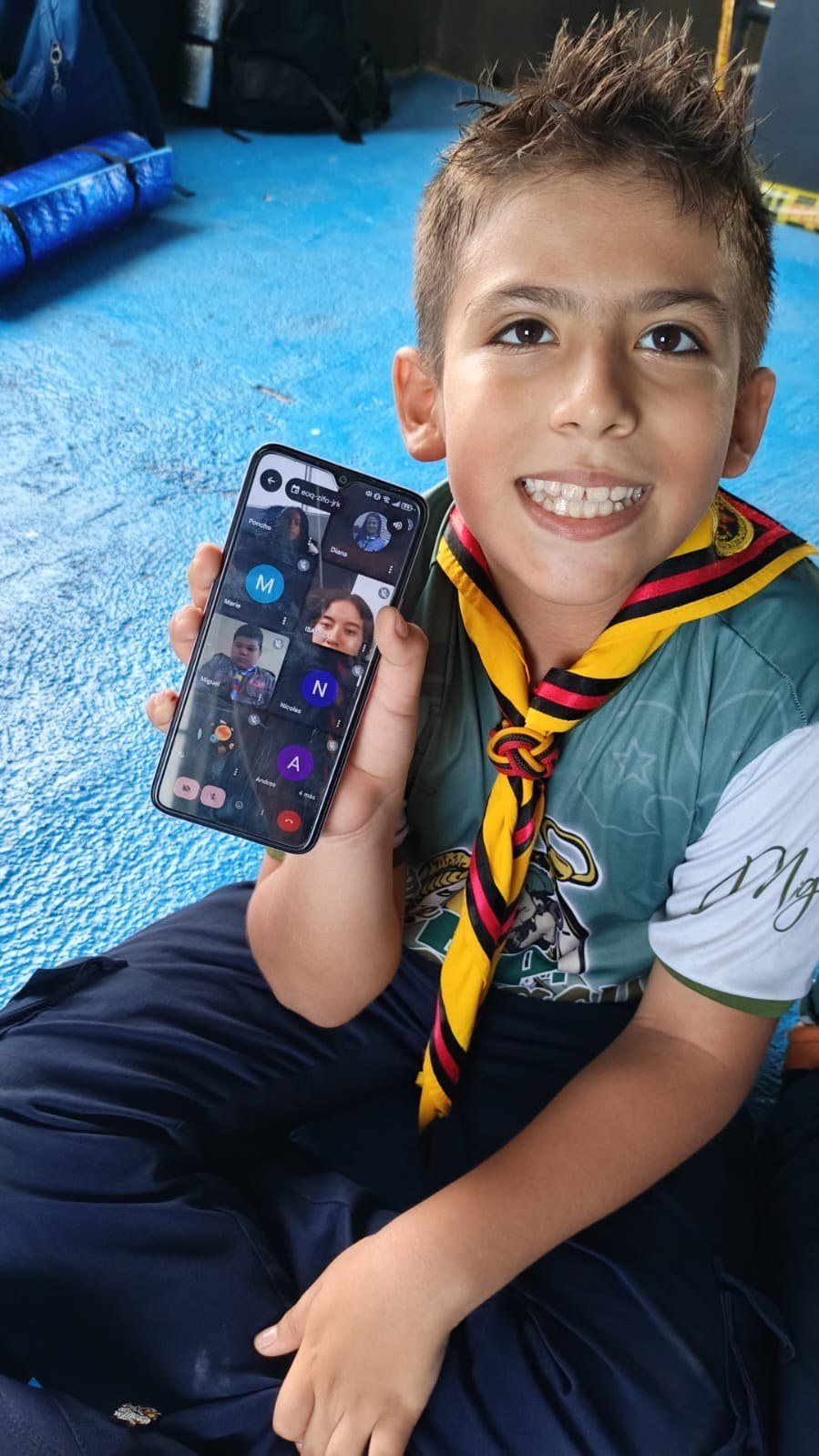 Un niño sonríe mostrando una videollamada del JOTI en su celular